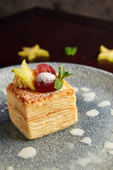 Piece of millefeuille cake on wooden background.