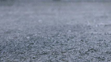 Rain drops in the water heavy on asphalt shade of black shadow and reflection of dark sky in the city. high contrast during autumn. soft focus.
