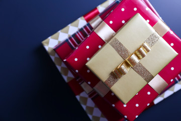 Bunch of christmas presents wrapped in red and golden paper tied with shiny silk bow. Multiple new years gifts in different wrapping. Top view, close up, copy space, background, flat lay