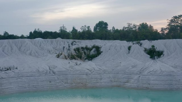 Aerial flyover view of Kaolin Lake mine pit at sunrise Bangka Island, Indonesia, drone approaches the lake wall