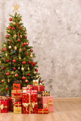 Decorated Christmas tree in soft yellow lights with bokeh effect background. Lofty apartment with traditional new year holiday decoration, intimate lighting. Close up, copy space.