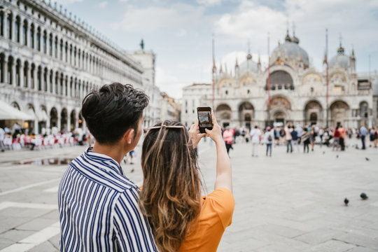 Loving couple in Venice, Italy - Millennials take a photo in the Piazza San Marco with the smartphone - Asian young people on vacation in Italy