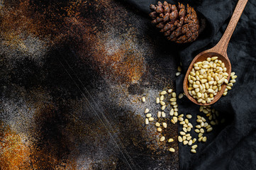 Pine nuts in the spoon and pine nut cone. Organic food. Black background. Top view. Space for text