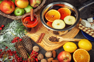 Hot drink mulled wine with citrus, apples and spices in a saucepan