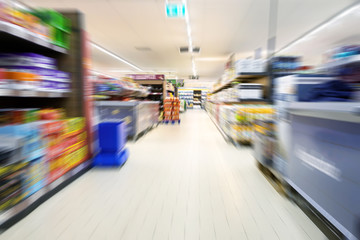 Abstract blurred supermarket aisle with modern shelves and goods for shopping, copy space