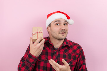 Happy surprised man in a red hat holding a gift with admiration on his face. Positive human...