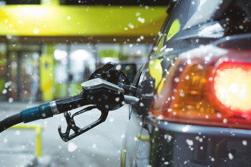 Black fuel nozzle in the car gas tank close up in winter.