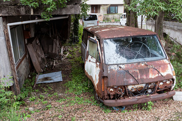 Rusty old car in the yard of an abandoned house.