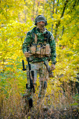 Airsoft, man in uniform stand with sniper rifle on autmn forest background