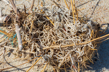 Environmental pollution - an old white cord and ist catches, lying on the beach as waste