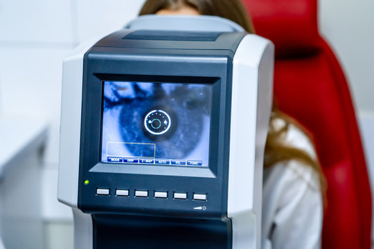 Woman looking at refractometer eye test machine in ophthalmology, vision correction concept