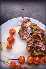 Food still life on a tray on a white plate baked meat and tomatoes on skewers decorated with red onions and olive oil