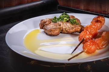 Food still life on a tray on a white plate baked meat and tomatoes on skewers decorated with red onions and olive oil