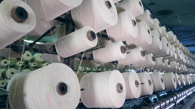 Many spools with threads spinning on a factory machine. industrial fabric production line