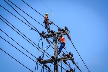 Electricians are climbing on electric poles to install and repair power lines.