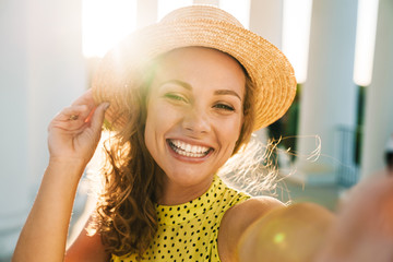 Pleased woman walking outdoors by street take a selfie