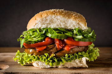 Vegan burger with seitan and vegetables on wooden table. Fake meat.	