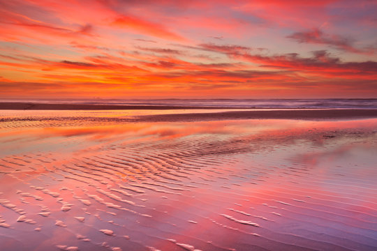 Beautiful sunset and reflections on the beach at low tide
