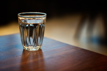 Water in clear glass on wooden table.