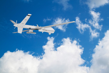 unmanned RC military drone flies against the backdrop of blue peaceful sky with white clouds