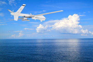 Fototapeta na wymiar unmanned RC military drone flies over calm sea with beautiful white clouds on blue sky