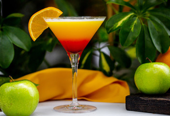 orange cocktail in martini glass garnished with orange juice