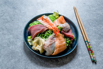 Sashimi Salad with Wakame, Seaweed, Salmon, Sea Bass, Shrimp, Kani, Mackerel Fish, Tuna served with Chopsticks.
