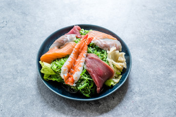Sashimi Salad with Wakame, Seaweed, Salmon, Sea Bass, Shrimp, Kani, Mackerel Fish, Tuna served with Chopsticks.