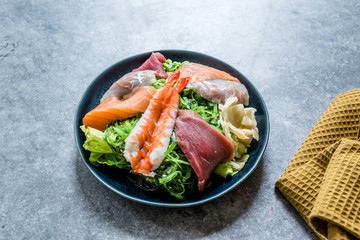 Sashimi Salad with Wakame, Seaweed, Salmon, Sea Bass, Shrimp, Kani, Mackerel Fish, Tuna served with Chopsticks.