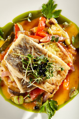 Pollock fish fillet with vegetables on white plate