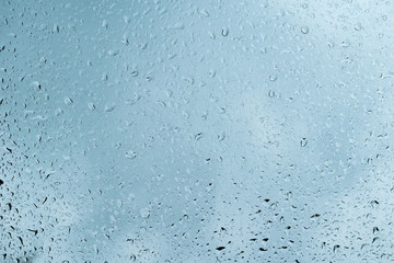 Raindrops on clear glass window blue cold morning rainy