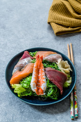 Sashimi Salad with Wakame, Seaweed, Salmon, Sea Bass, Shrimp, Kani, Mackerel Fish, Tuna served with Chopsticks.
