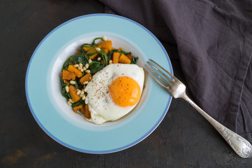 Sunny side up egg with spinach and pumpkin.