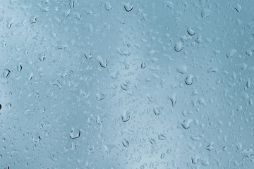 Raindrops on clear glass window blue cold morning rainy