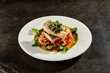 Pollock fish fillet with vegetables on white plate
