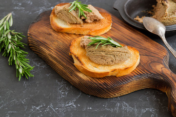 homemade meat pate on toasted crusty bread. dark photo style.