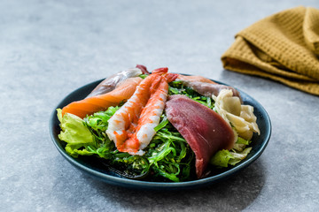 Sashimi Salad with Wakame, Seaweed, Salmon, Sea Bass, Shrimp, Kani, Mackerel Fish, Tuna served with Chopsticks.