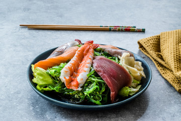 Sashimi Salad with Wakame, Seaweed, Salmon, Sea Bass, Shrimp, Kani, Mackerel Fish, Tuna served with Chopsticks.