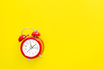 Red vintage alarm clock on a yellow background