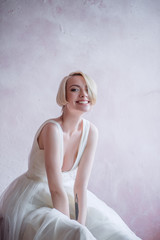 A sweet, tender, beautiful and courageous bride in an elegant wedding dress and cool shoes. Long veil of the bride. Bride girl with short hair.