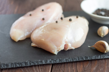 Raw chicken fillet on a stone Board with pepper and garlic.Cooking
