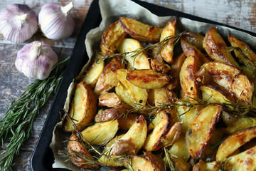 Selective focus. Rustic golden baked potato. Sliced baked potato with spices, garlic and rosemary. Vegan lunch. Christmas dish. Macro.