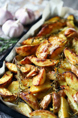 Selective focus. Rustic golden baked potato. Sliced baked potato with spices, garlic and rosemary. Vegan lunch. Christmas dish. Macro.