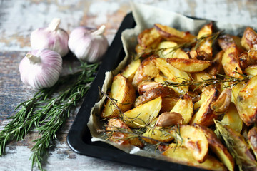 Selective focus. Rustic golden baked potato. Sliced baked potato with spices, garlic and rosemary. Vegan lunch. Christmas dish. Macro.