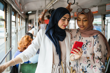 Arab italian friends on the tram in Italy - Millennials women talking during the trip to the city...