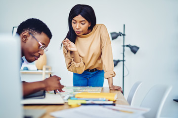 Male and female colleagues concentrated on planning route for exploring spending time together,...