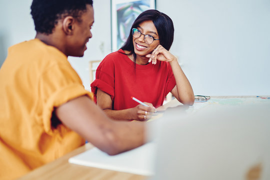 Cheerful african american students talking to each other spending free time together enjoy communication, smiling dark skinned woman having interview with male applicant ask questions and make notes.