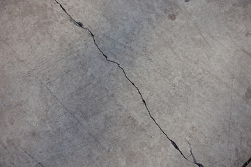 Diagonal crack on light grey concrete slab from above