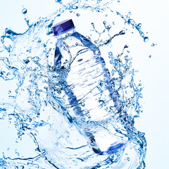 Splashes of water around a plastic bottle on a light background. Drinking clear water.