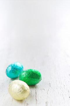 Small chocolate Easter eggs on a rustic white background